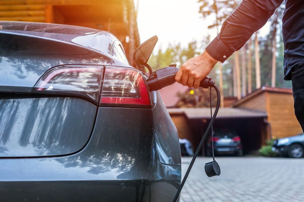 Hand plugging charge cable into EV
