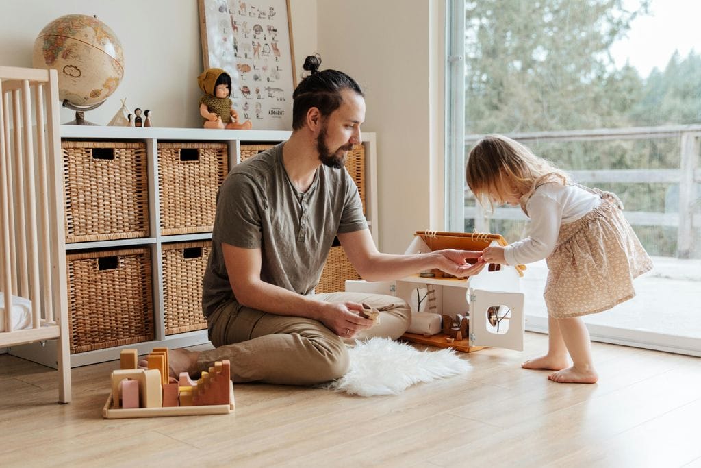 Father ad daughter playing with toys in playroom by a window