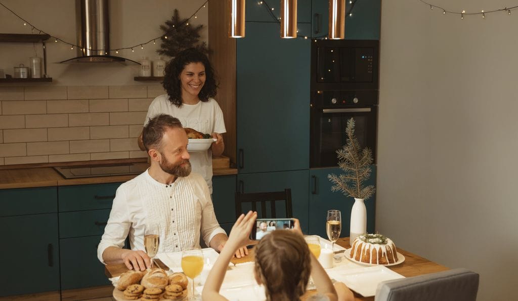 Family gathered around a dining table in a modern kitchen, sharing a meal under warm lighting.