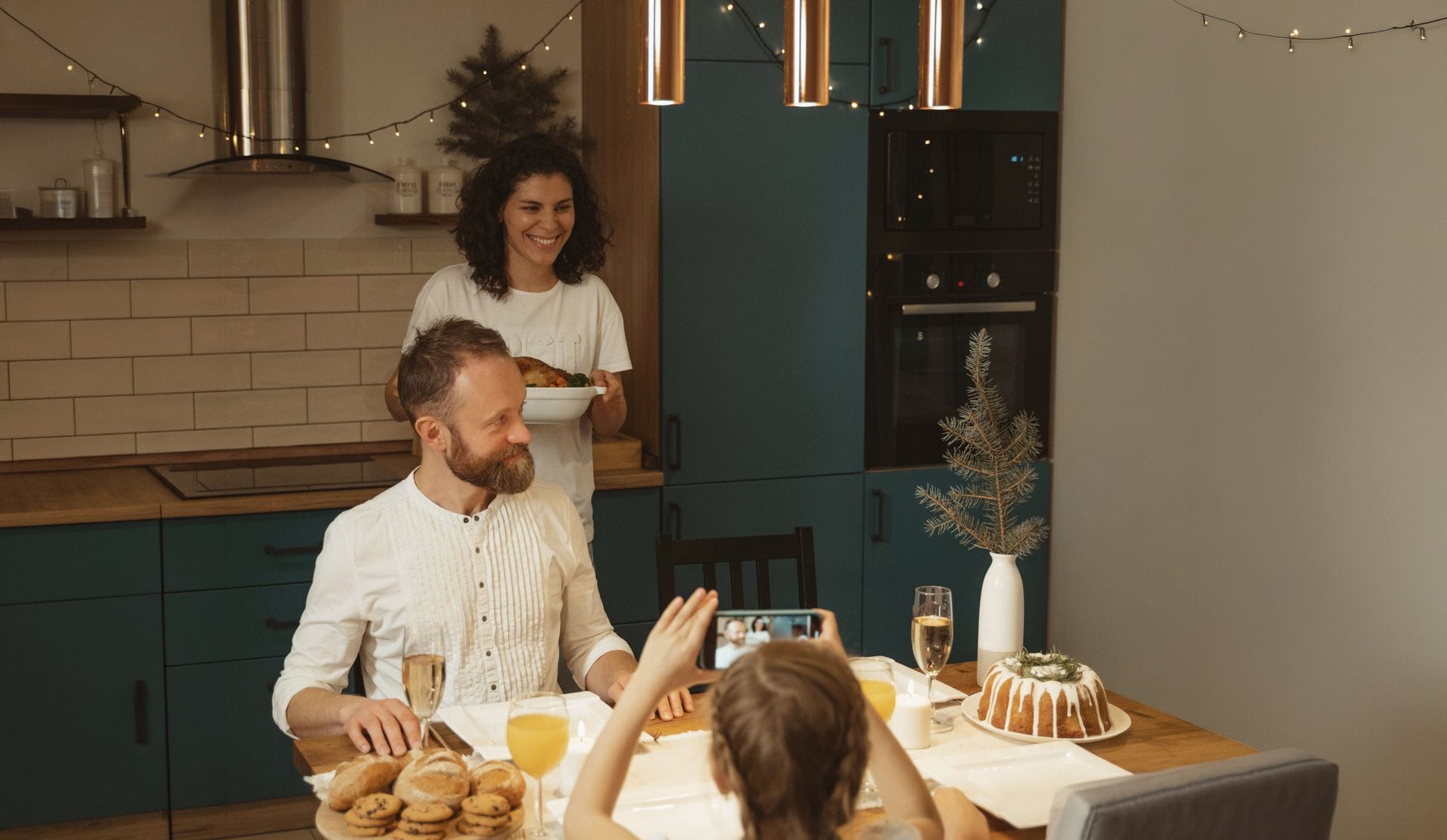 Family gathered around a dining table in a modern kitchen, sharing a meal under warm lighting.